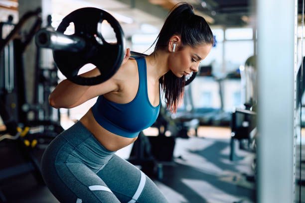 young sportswoman working out with a barbell in health club.
